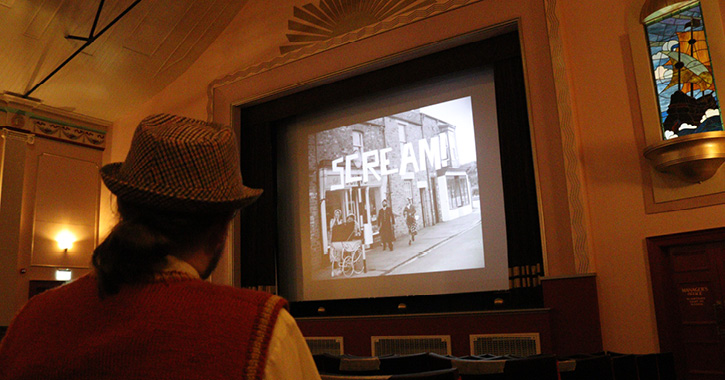 man sat watching a movie inside the new 1950s cinema at Beamish Museum